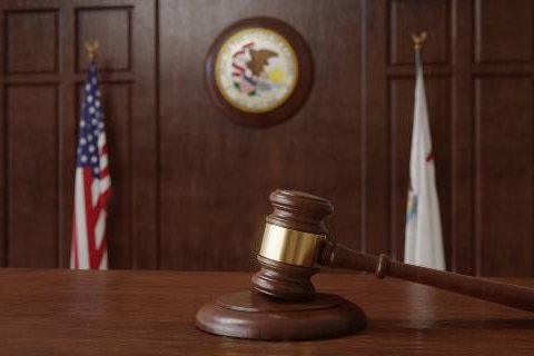 Gavel and flags with Illinois seal in courtroom