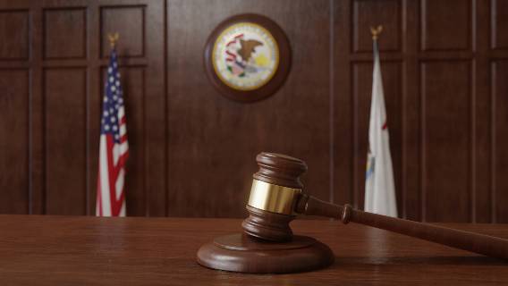 Gavel and flags with Illinois seal in courtroom