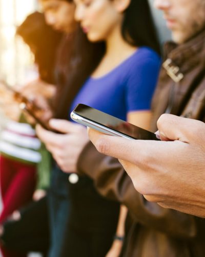 Row of young adults on cellphones
