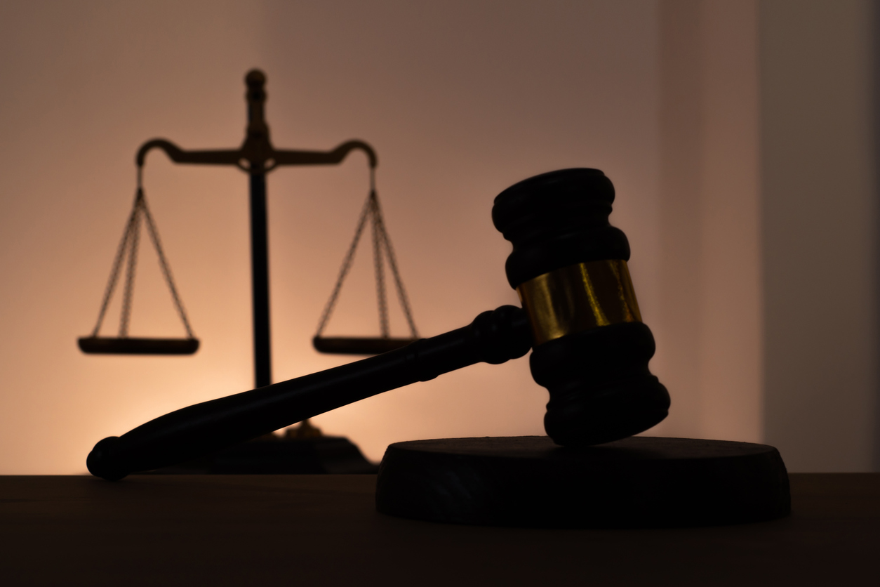 Silhouettes of a judge's gavel and scales of justice. Symbol of law, rights, legal protection, and the court.