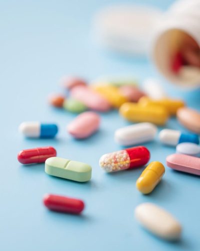 Multicolored pills scattered from white plastic medicine container
