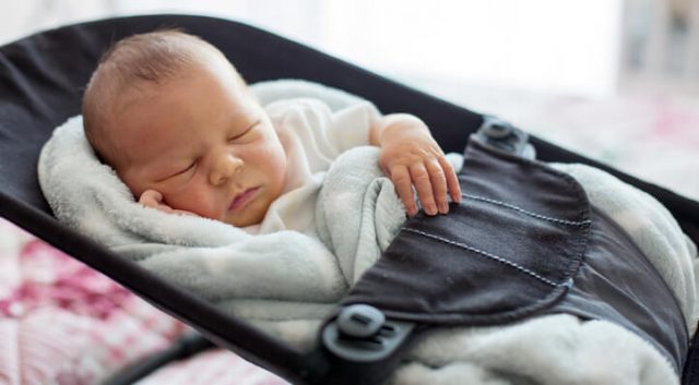 Newborn sleeping in inclined swing