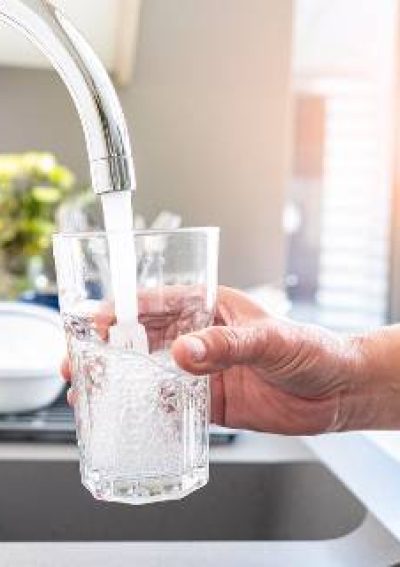 Woman with glass getting water from tap