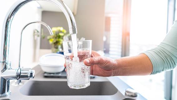 Woman with glass getting water from tap