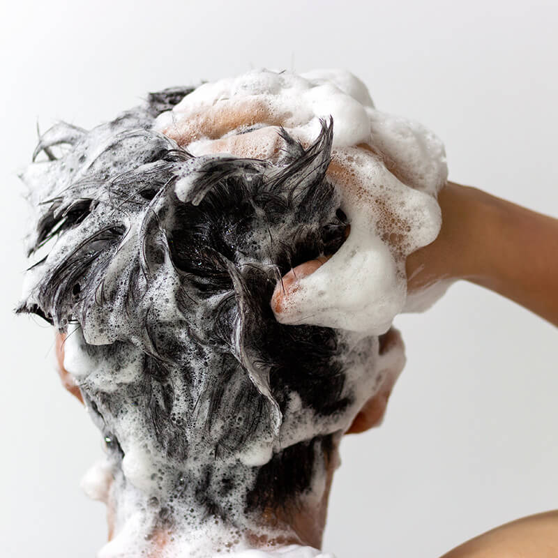 Person washing hair with shampoo