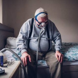 Elderly man on bed with CPAP machine