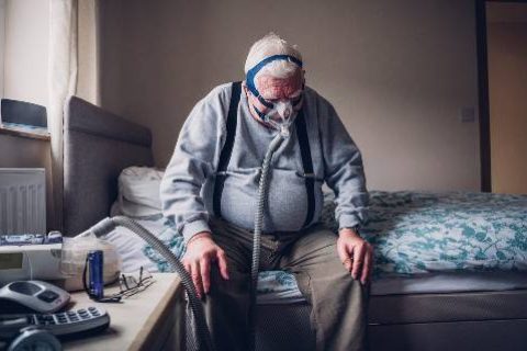 Elderly man on bed with CPAP machine