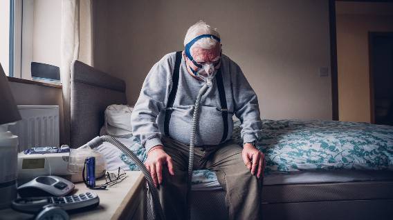 Elderly man on bed with CPAP machine