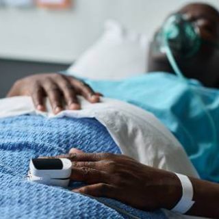 Man in hospital bed with oximeter on finger