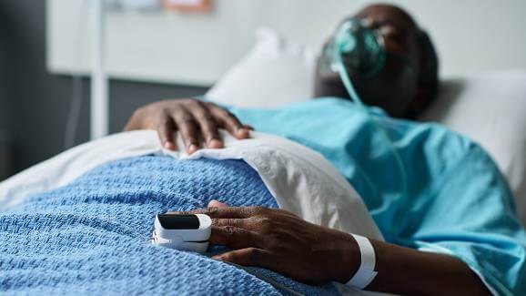 Man in hospital bed with oximeter on finger