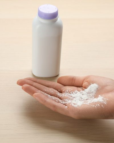 Woman holding powder in her hand at wooden table.