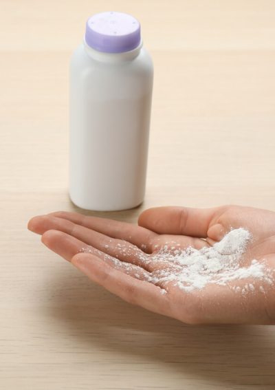 Woman holding powder in her hand at wooden table.