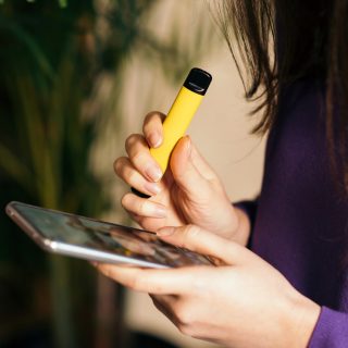 Teen vaping and looking at phone