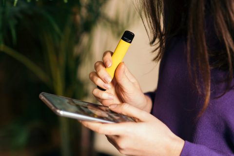 Teen vaping and looking at phone