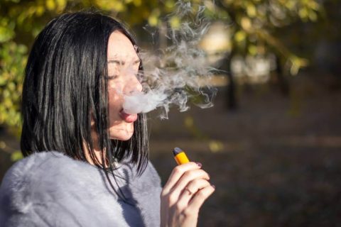 Teen girl vaping with e-cigarette