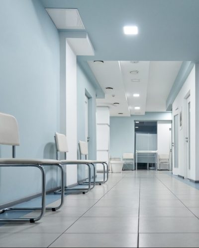 Empty modern hospital corridor, clinic hallway interior background with white chairs for patients waiting for doctor visit. Contemporary waiting room in medical office.