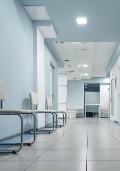 Empty modern hospital corridor, clinic hallway interior background with white chairs for patients waiting for doctor visit. Contemporary waiting room in medical office.