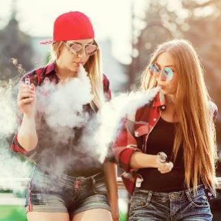 Two teen girls vaping outdoors