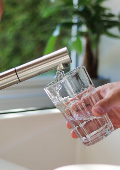 Close up of male hands pouring tap water into a glass in the kitchen.
