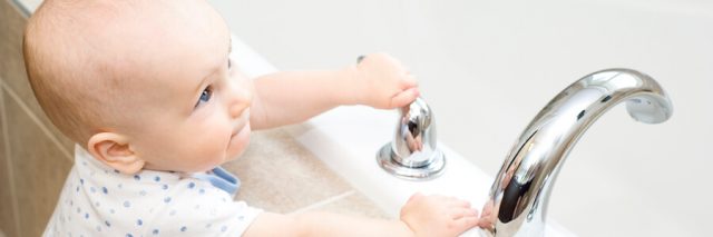 Baby playing with water faucet
