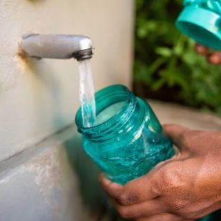 Hands filling water bottle from tap