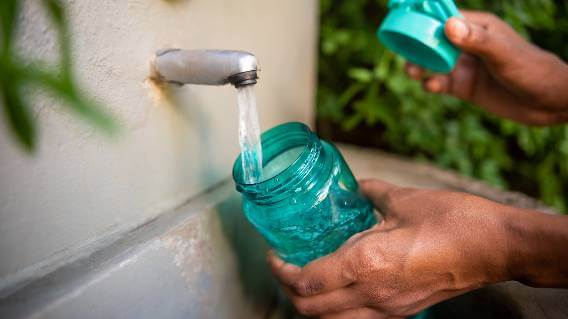 Hands filling water bottle from tap