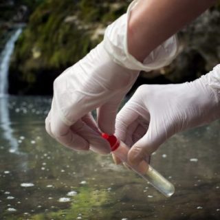 Gloved hands testing water outdoors