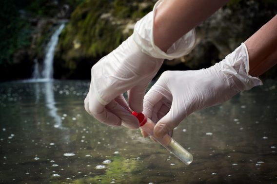 Gloved hands testing water outdoors