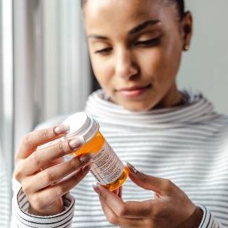 Woman looking at label on pill bottle