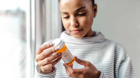 Woman looking at label on pill bottle