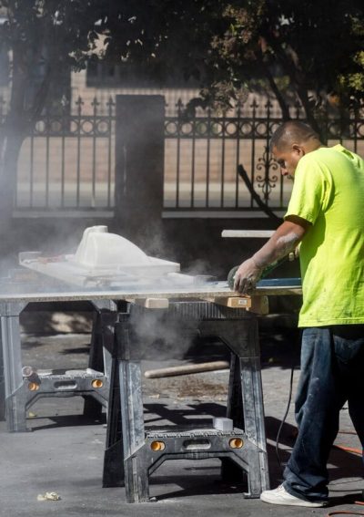 Worker cutting granite without protection.